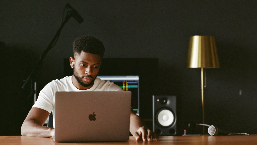 DistroKid vs TuneCore vs UnitedMasters vs Amuse: Music Distribution Compared (2026) 4 Independent artist at a home studio laptop, comparing music distribution platforms