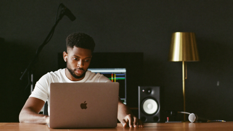 Independent artist at a home studio laptop, comparing music distribution platforms