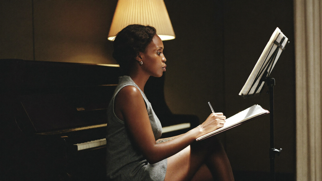 Music Publishing 101: Performance, Mechanical and Sync Rights Explained 6 Songwriter at an upright piano writing notes in a notebook by lamplight