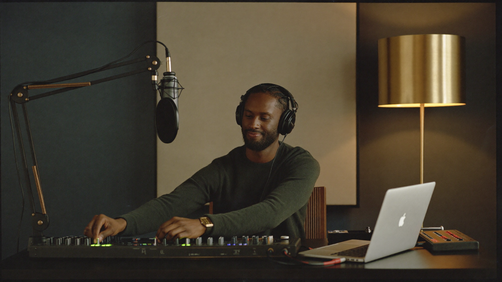 The Complete Home Studio Setup Under $1,000 (2026) 6 Independent artist wearing headphones adjusting an audio interface at a home studio desk