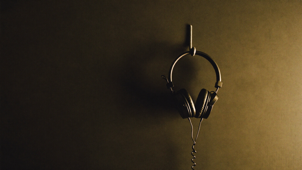 Best Studio Headphones for Mixing Under $200 (2026) 4 A pair of studio headphones hanging on a hook against a dark studio wall