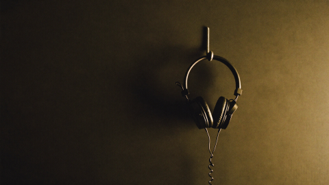 A pair of studio headphones hanging on a hook against a dark studio wall
