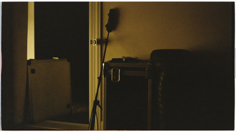 A hard flight case and gear bag stacked by a doorway at night with car keys resting on top